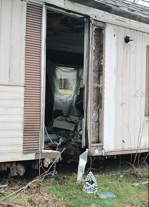 Abandoned mobile home at Lily of the Valley Campground, Thompson, Ohio, with a broken entrance, cluttered interior, and